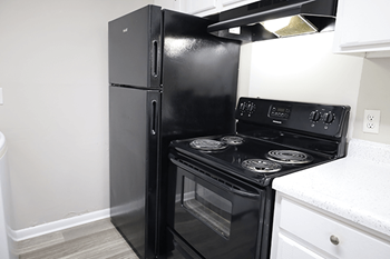A black refrigerator and stove in a kitchen.