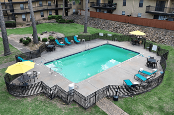 A small pool surrounded by a fence and chairs.