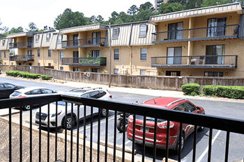 A red car is parked on the street in front of an apartment building.