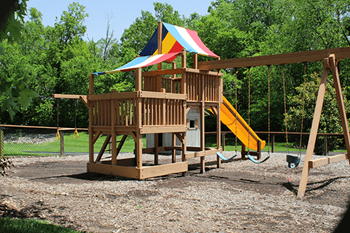 a playground with a swing set and a tower with a slide