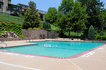 a swimming pool with trees and a building in the background