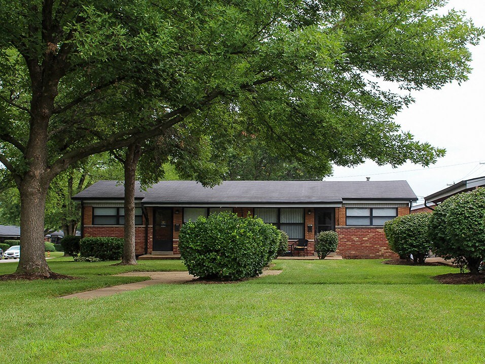 apartment complex with a yard and trees in front of it