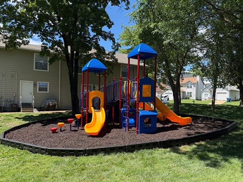 A playground with a blue and yellow slide and a red and blue tower.