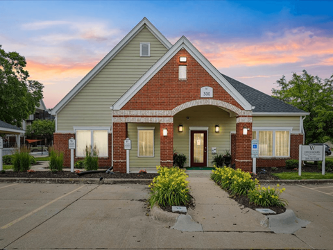 the front of a house with a driveway and a sunset in the background