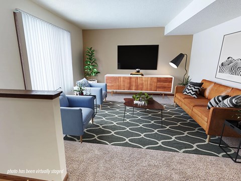 A living room with a blue chair, a brown couch, and a television on the wall.