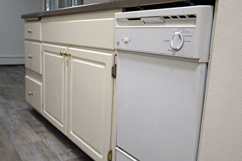 A white dishwasher with a silver knob is built into a kitchen cabinet.