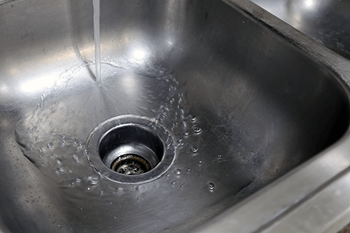 A stainless steel sink with water running from the tap.