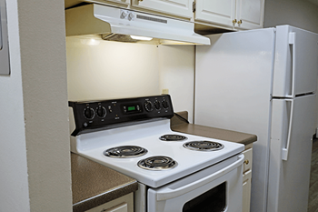 A white electric stove with four burners is in a kitchen.