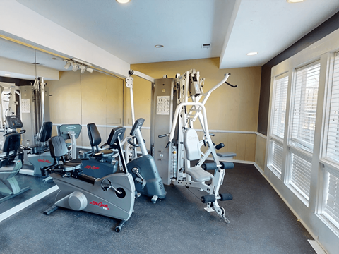 A gym with a treadmill, elliptical trainer and a weight machine.