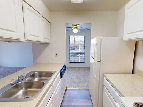 A kitchen with white cabinets and a stainless steel sink.