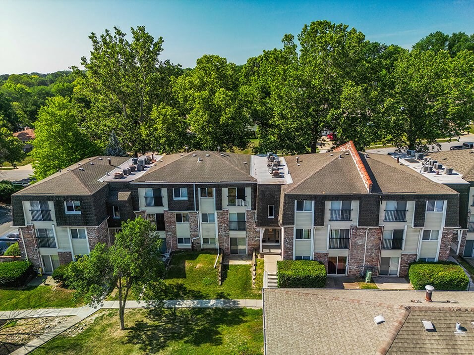 an aerial view of a large apartment complex with trees in the background