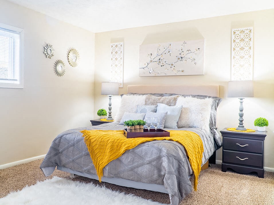 a bedroom with white walls and a yellow blanket on the bed