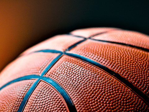 A close up of a basketball with a focus on the textured surface and the blue lines.