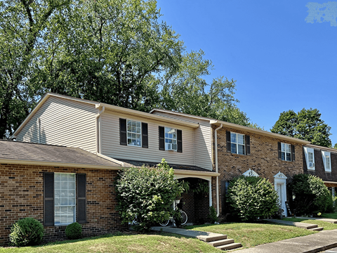 A residential house with a front yard and a tree.