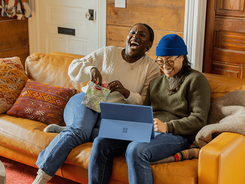 Two people sitting on a couch with a laptop.