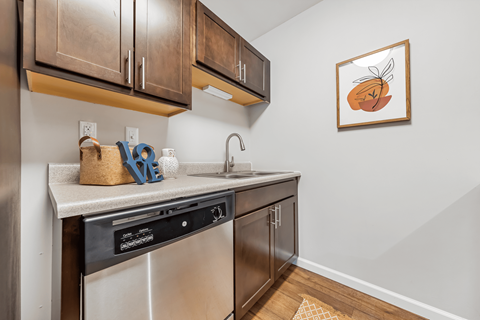 A kitchen with brown cabinets and a framed picture of a pumpkin on the wall.