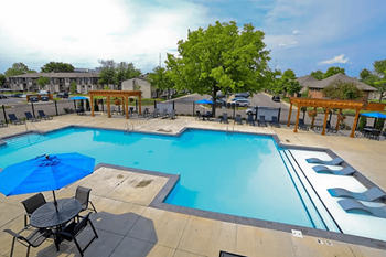a swimming pool with tables and chairs and a blue umbrella