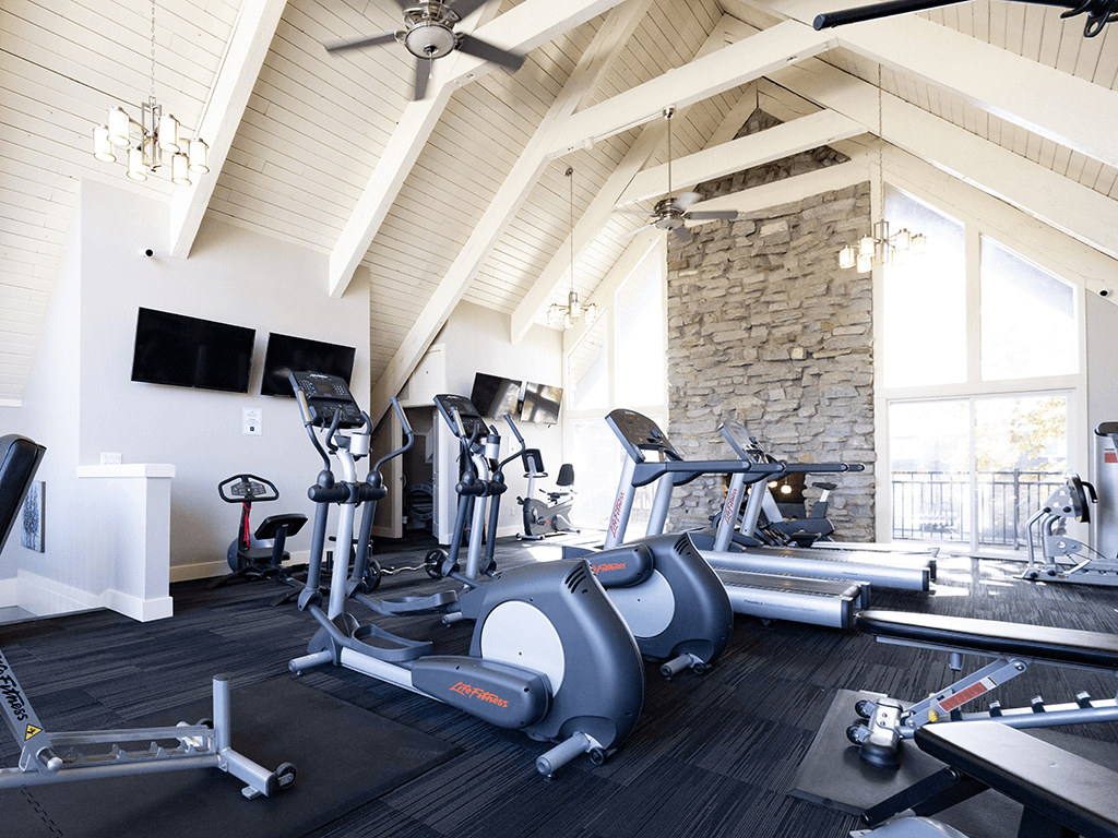 a gym with exercise machines and a stone fireplace