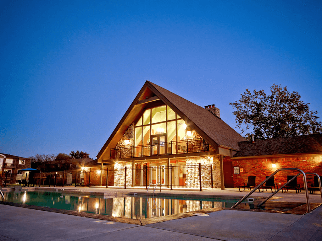 a  apartment clubhouse with a swimming pool at night