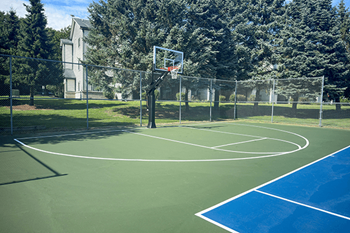 a basketball hoop on a green and blue court in a park
