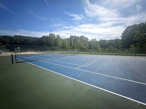 a tennis court on a sunny day with trees