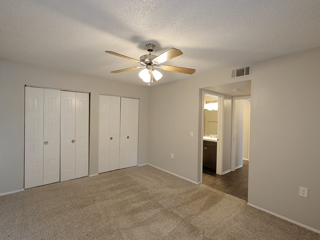 an empty living room with a ceiling fan and closet