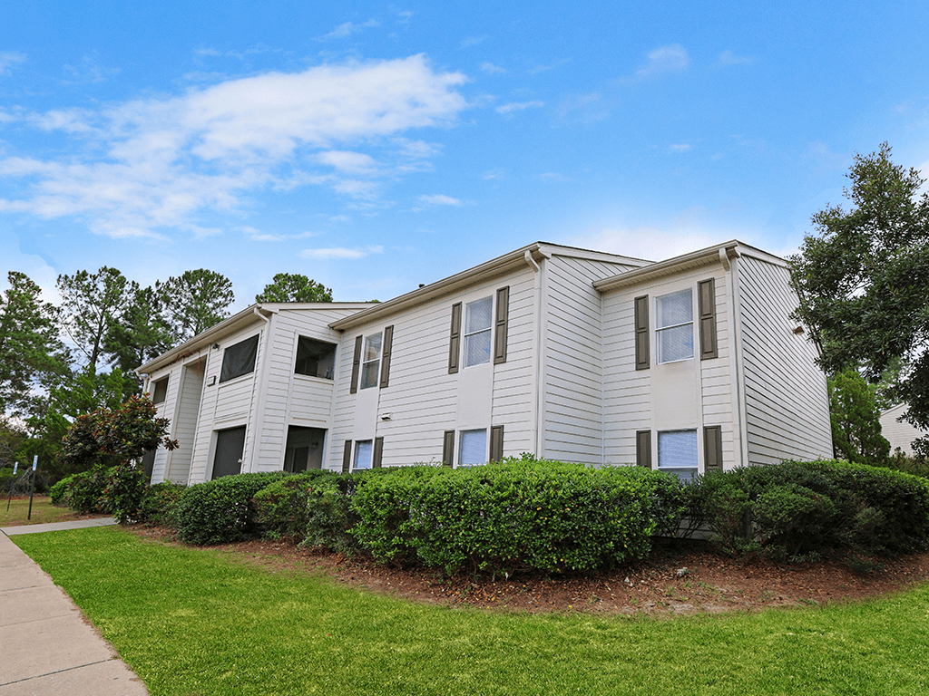 an apartment building with white siding and a sidewalk