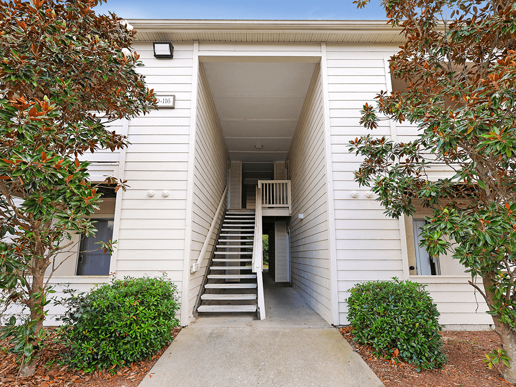 the exterior of a white building with stairs and a sidewalk