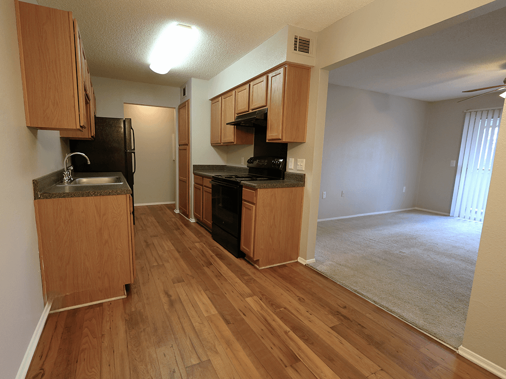an empty kitchen and living room with wood flooring and