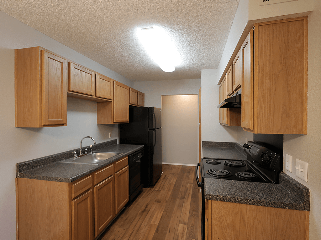 an empty kitchen with wood cabinets and a black stove and refrigerator