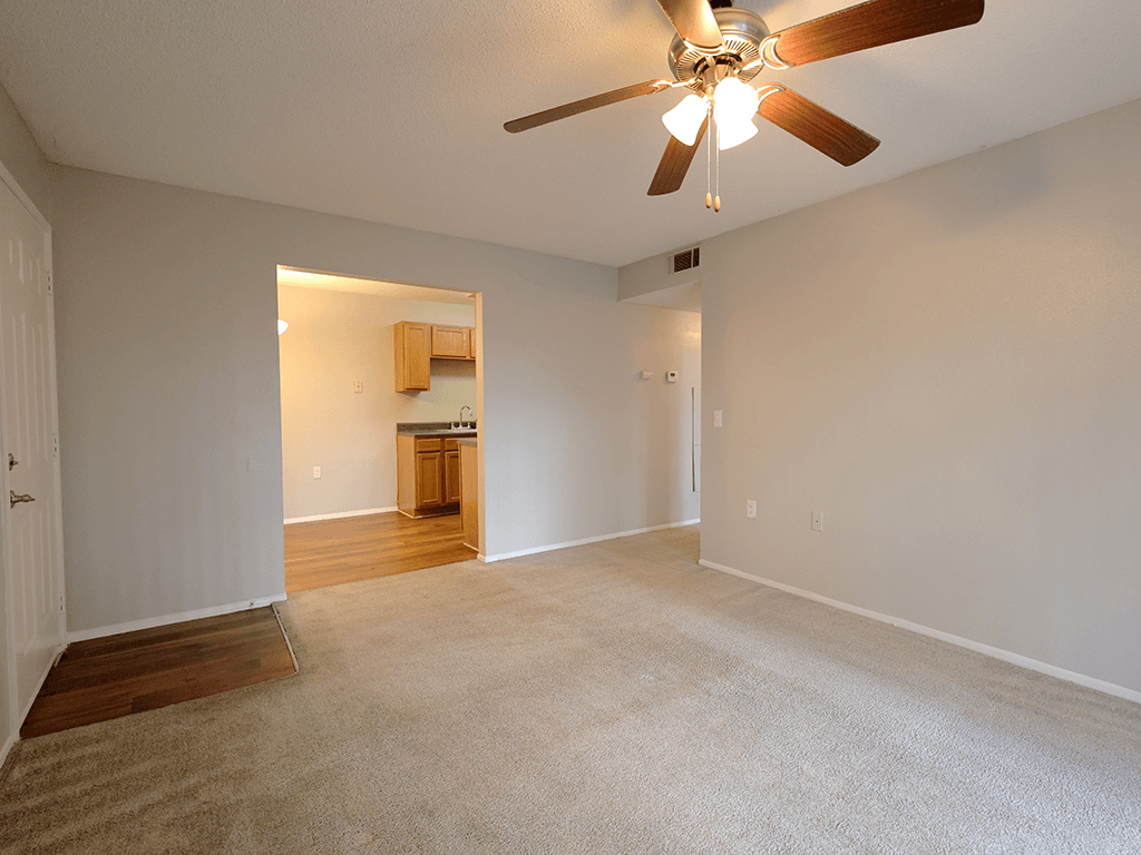 an empty living room with a ceiling fan