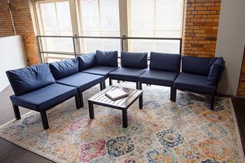 A blue couch with a coffee table in front of a brick wall.