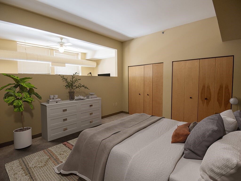 A bedroom with a bed, dresser, and plant.
