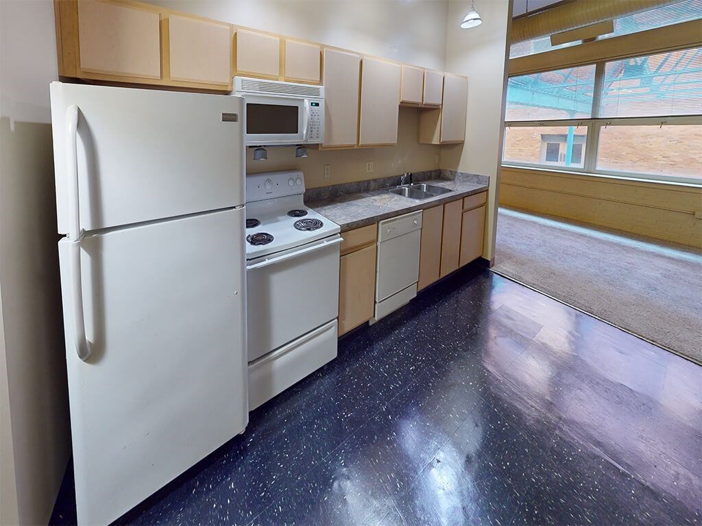 A kitchen with a white fridge, microwave, and stove top oven.