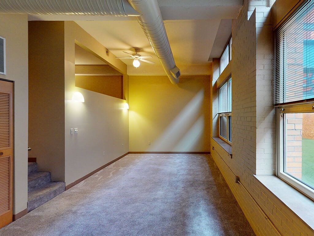 A long hallway with a carpeted floor and a window on the right side.