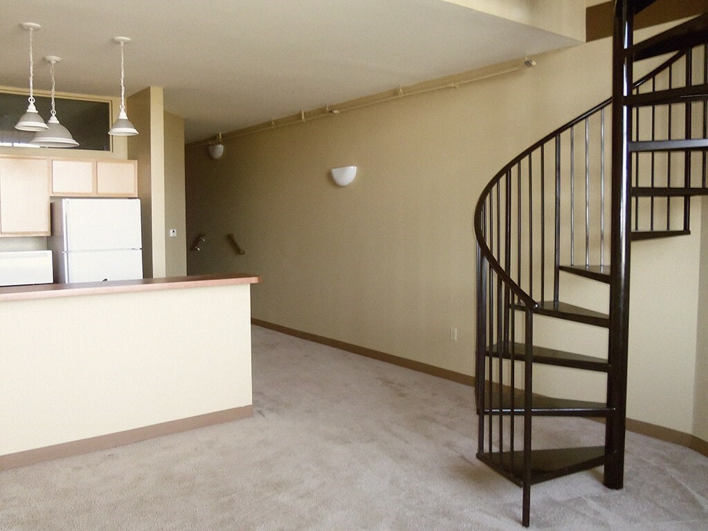 A spiral staircase in a room with a kitchen area.