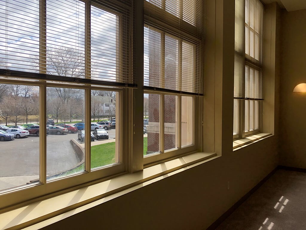 A view of a parking lot through a window with blinds.