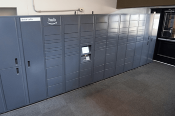 A row of Amazon lockers are lined up against a wall.