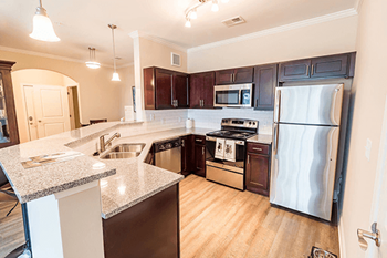 A kitchen with dark wood cabinets and stainless steel appliances.