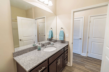 A bathroom with a sink, mirror, and wooden floors.