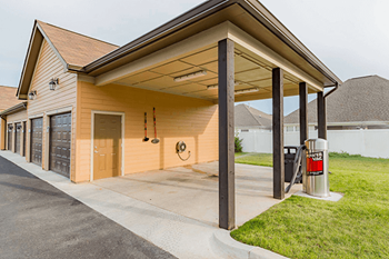 A garage with a red fire extinguisher on the grass.