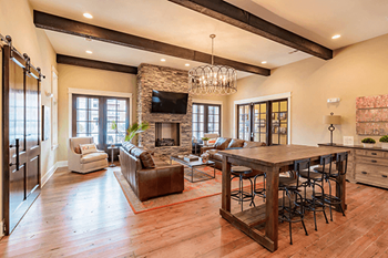 A large open living room with a stone fireplace and a long wooden table.
