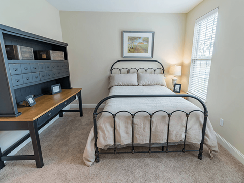 A bedroom with a large bed and a wooden nightstand.
