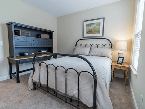 A bedroom with a bed, nightstand, and a dresser.