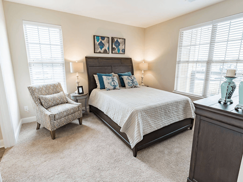 A bedroom with a bed, chair, and two lamps.