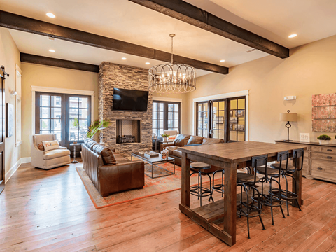 A large open living room with a stone fireplace and a long wooden table.