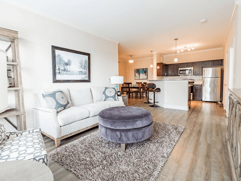 A living room with a white couch and a grey ottoman.