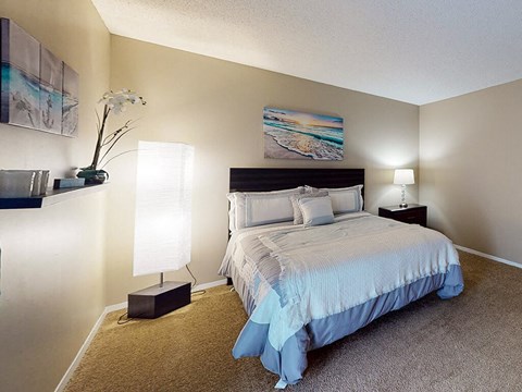 A bedroom with a bed, nightstand, and lamp.
