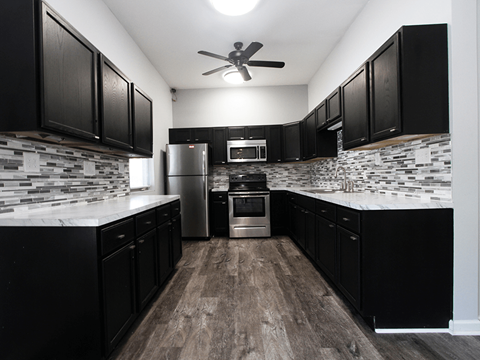 a kitchen with black cabinets and white countertops and a stainless steel refrigerator