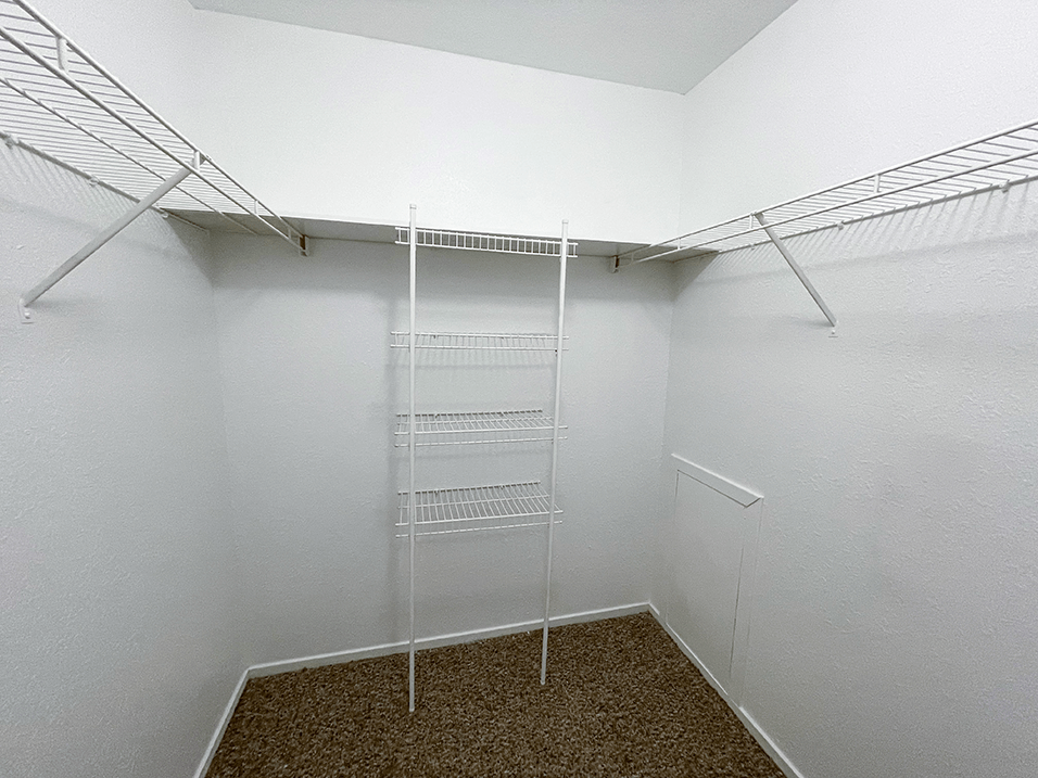 a spacious walk in closet in a bedroom with white walls